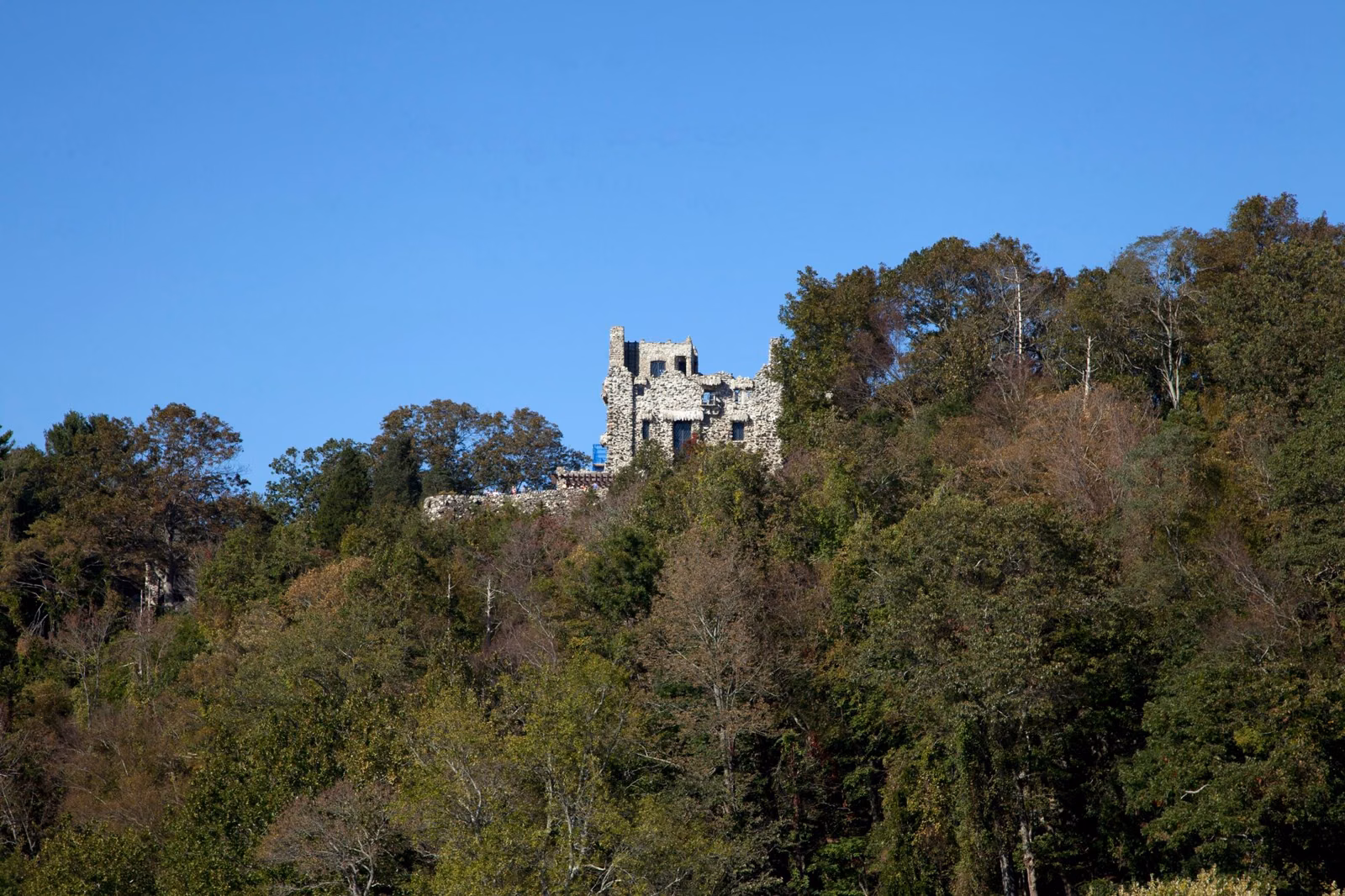 Stone castle on a wooded hilltop above the river, seen from the water