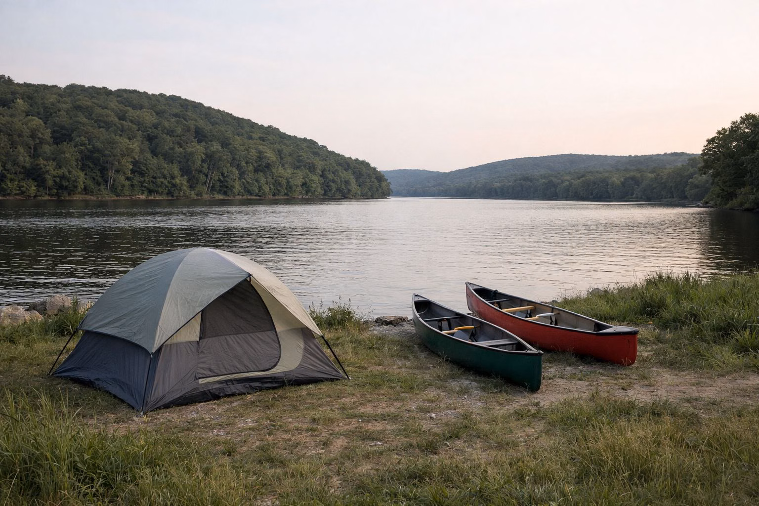 Small tent in a riverside clearing with two canoes pulled up on the bank