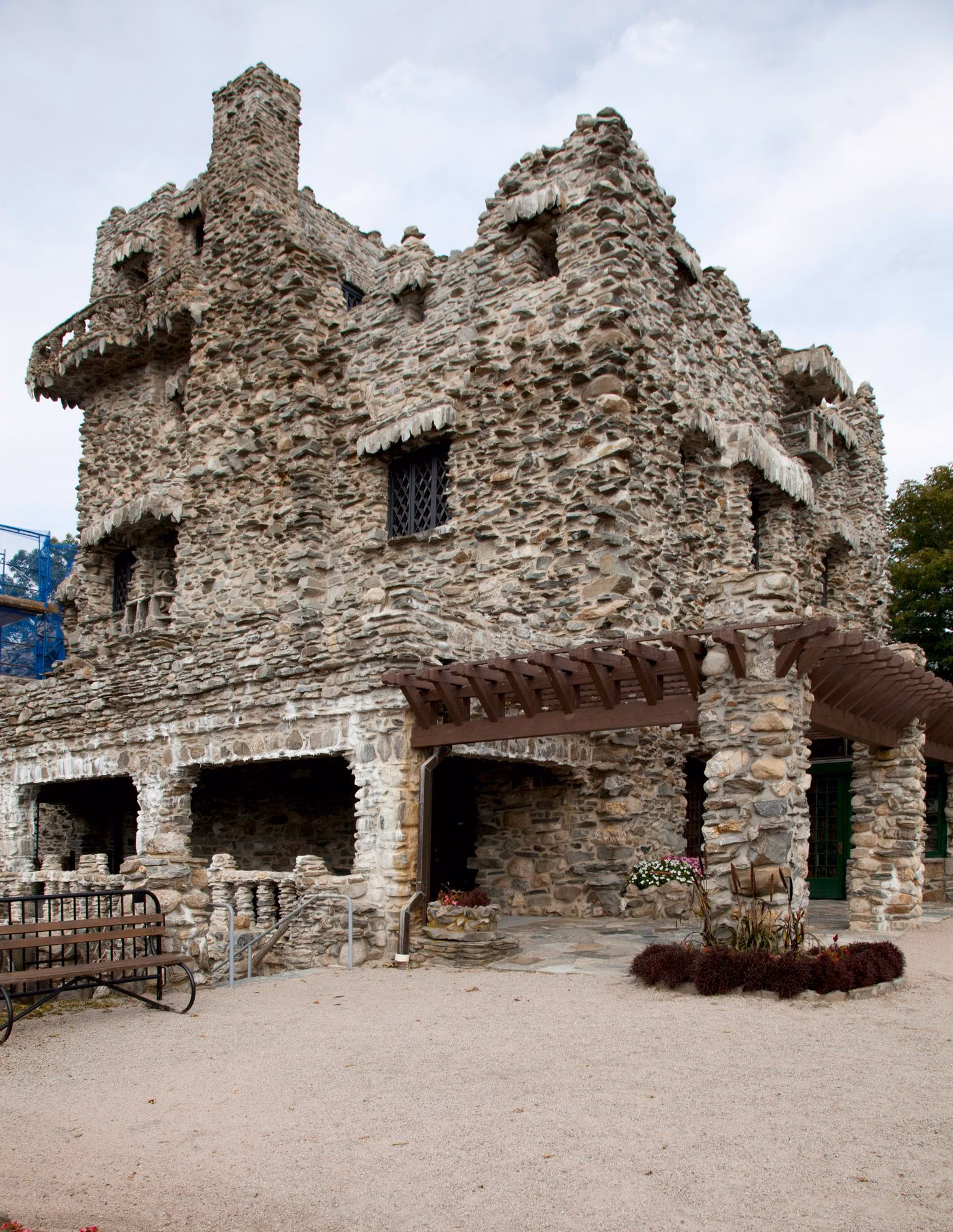 Corner of the fieldstone castle with a wooden pergola and benches