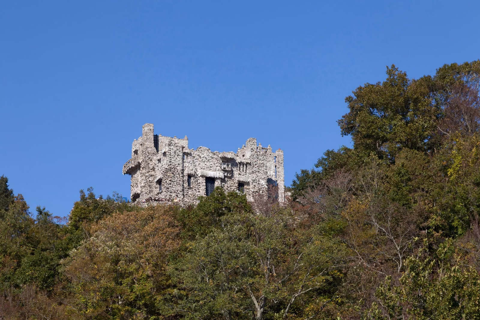 Stone castle on top of a steep wooded bluff under a blue sky