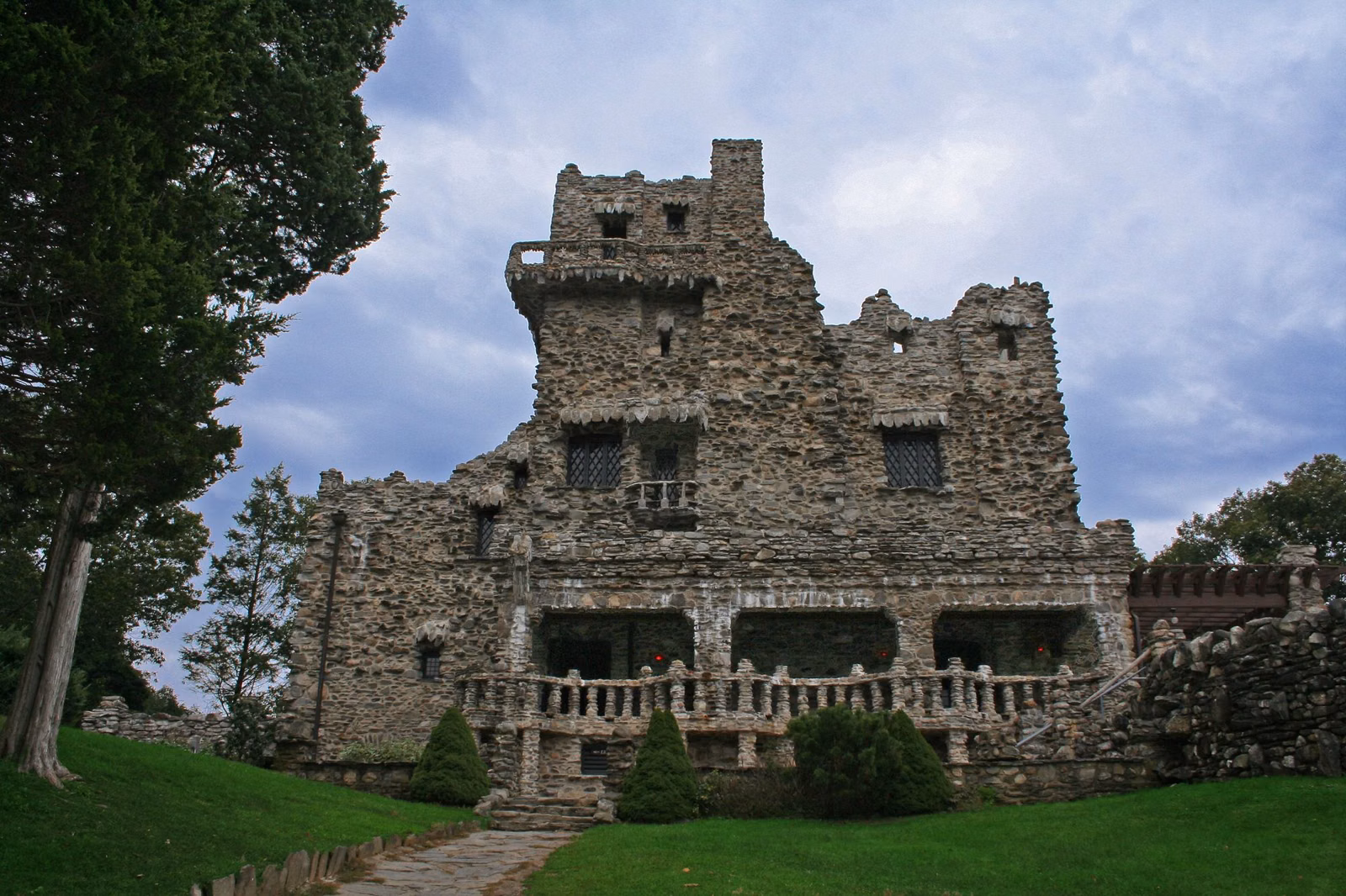 Fieldstone castle front with a long stone porch above a green lawn
