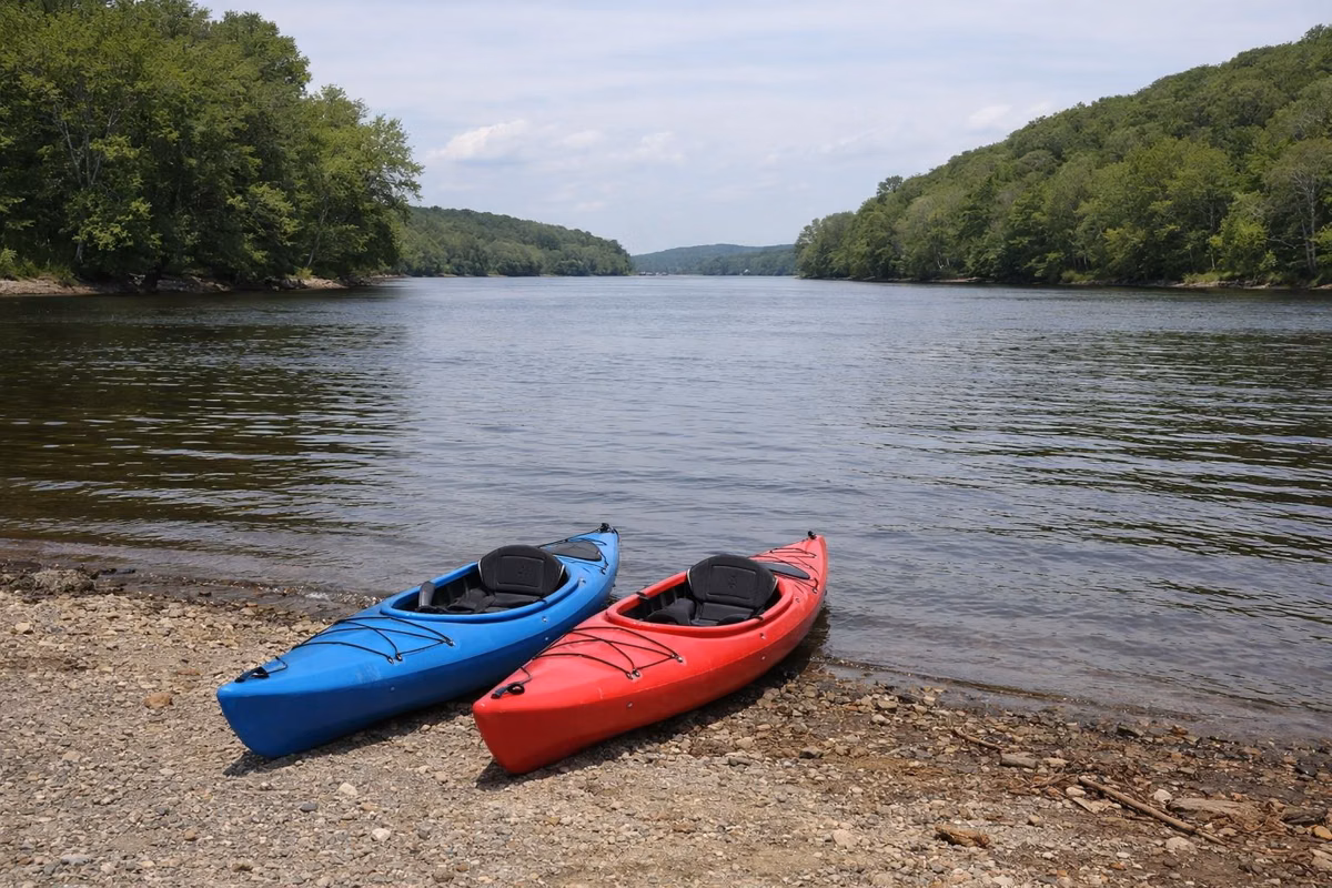 Two kayaks on a gravel launch at the edge of a wide river