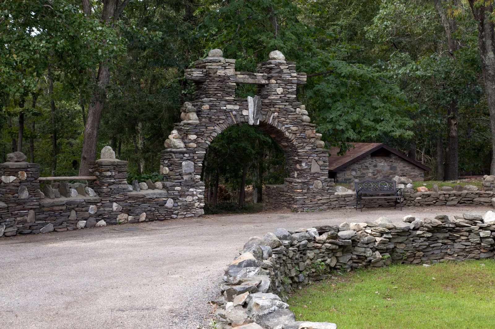 Stone gate and a curving road edged by a fieldstone wall